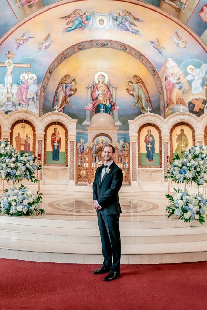 A groom posing for a classic portrait on the day of his Greek Orthodox wedding