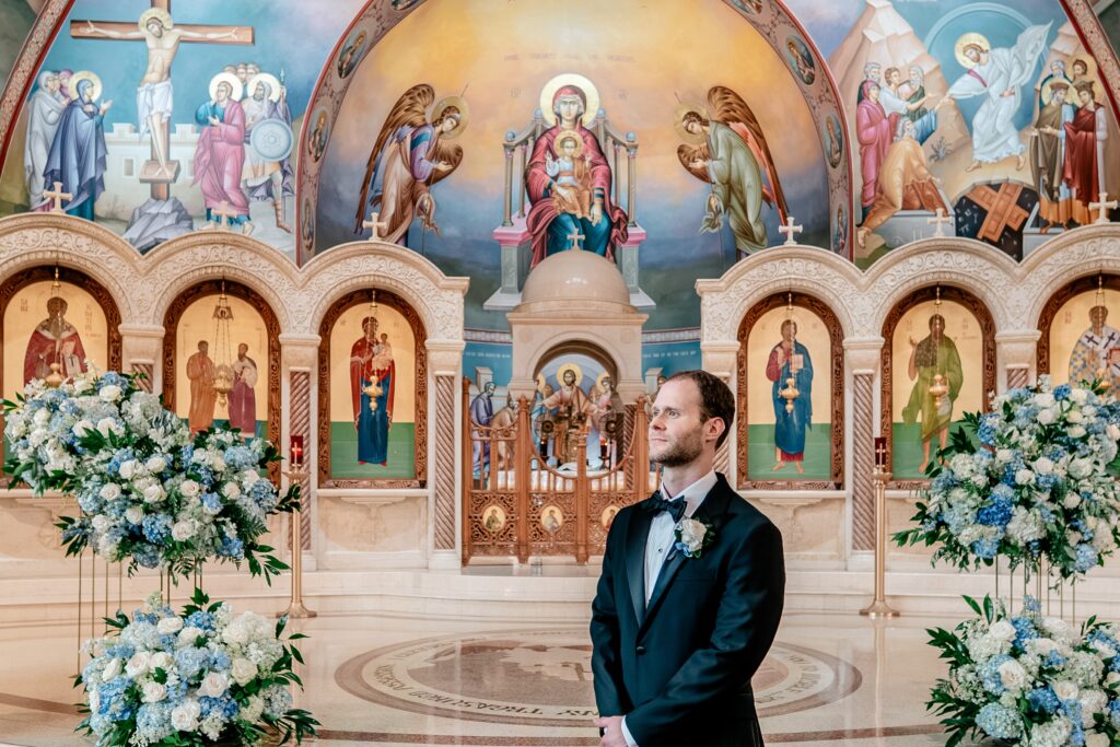 A groom looking off camera in the front of the church after his wedding ceremony
