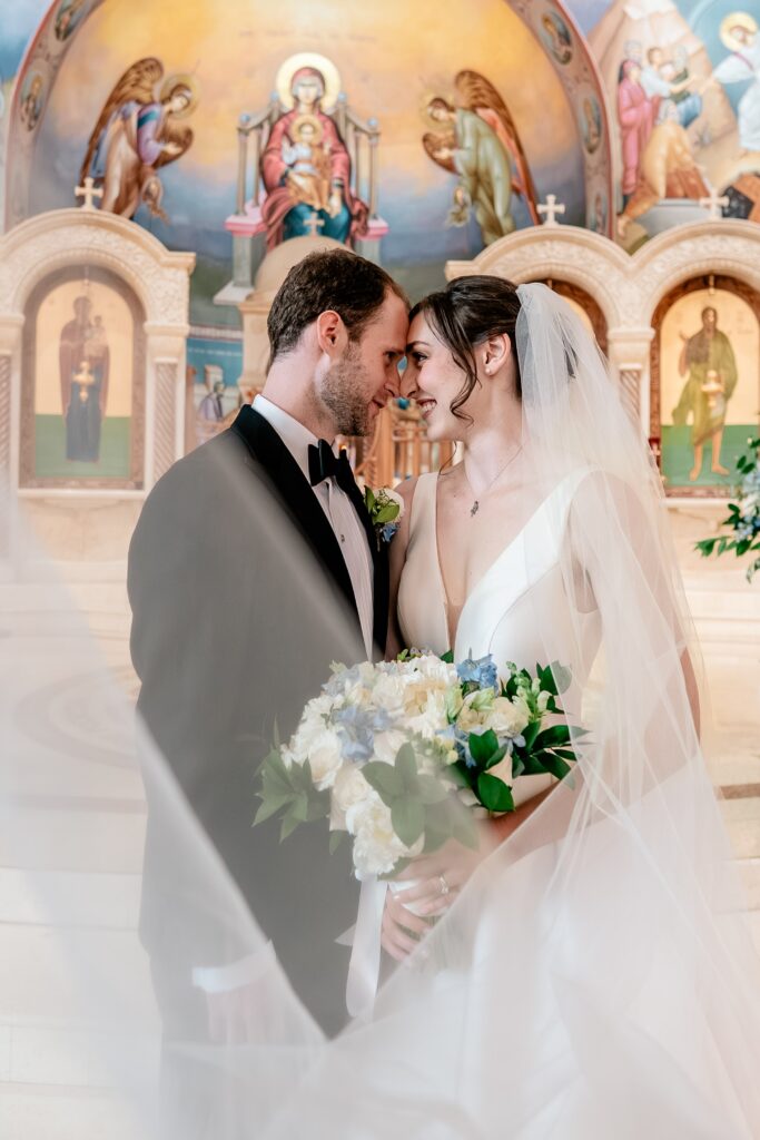 A bride and groom posing forehead to forehead during their Sts. Peter and Paul Antiochian Orthodox Church wedding in Potomac, Maryland