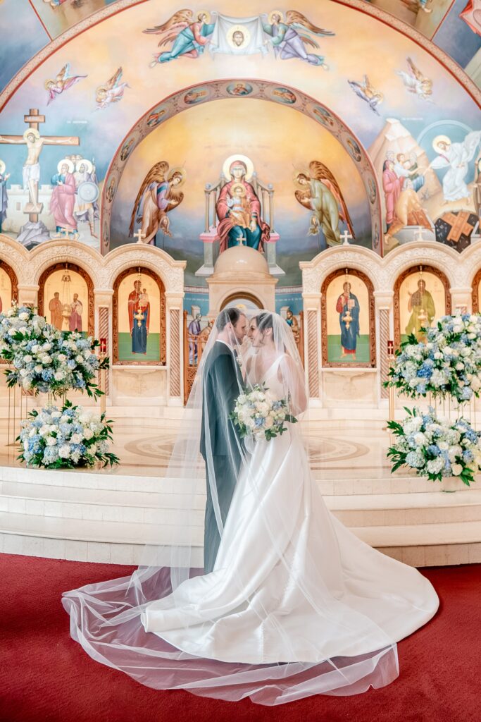A bride and groom under the veil together during their Greek Orthodox wedding