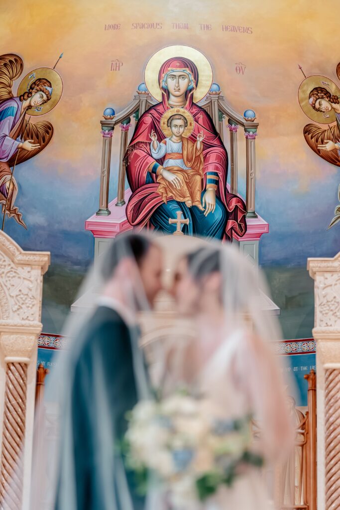 An image of the Madonna and Child with a bride and groom in the foreground by a colorful wedding photographer