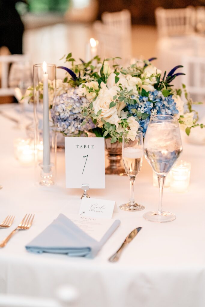 A reception table with glowing candles and hydrangea flower arrangements after a Greek Orthodox wedding
