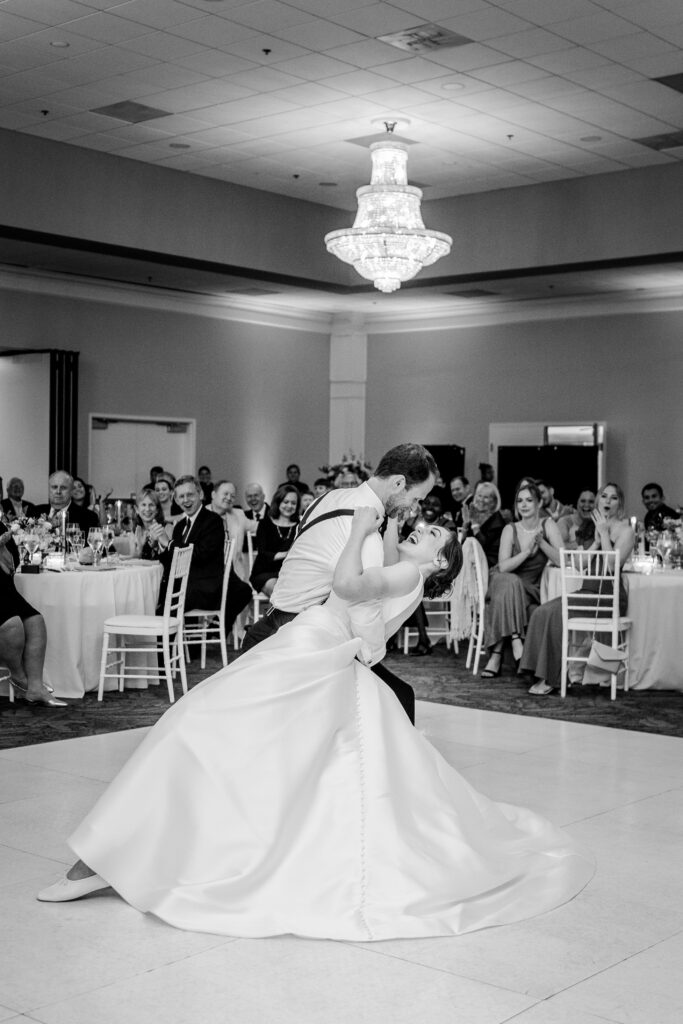 A bride and groom laughing as he dips her during their first dance