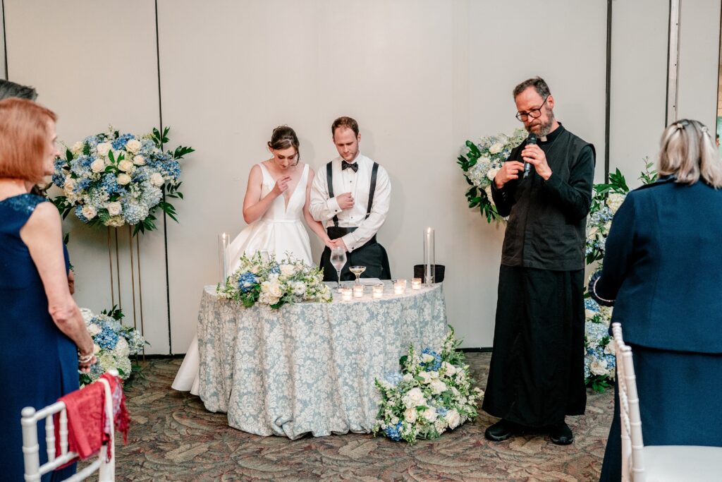 A priest giving a blessing for the meal at the reception for a Sts. Peter and Paul Antiochian Orthodox Church wedding in Potomac, Maryland