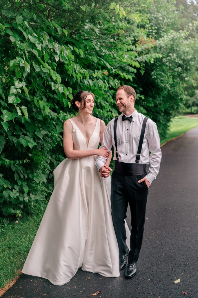 A bride and groom laughing together as they walk along a path for their Sts. Peter and Paul Antiochian Orthodox Church wedding in Potomac, Maryland