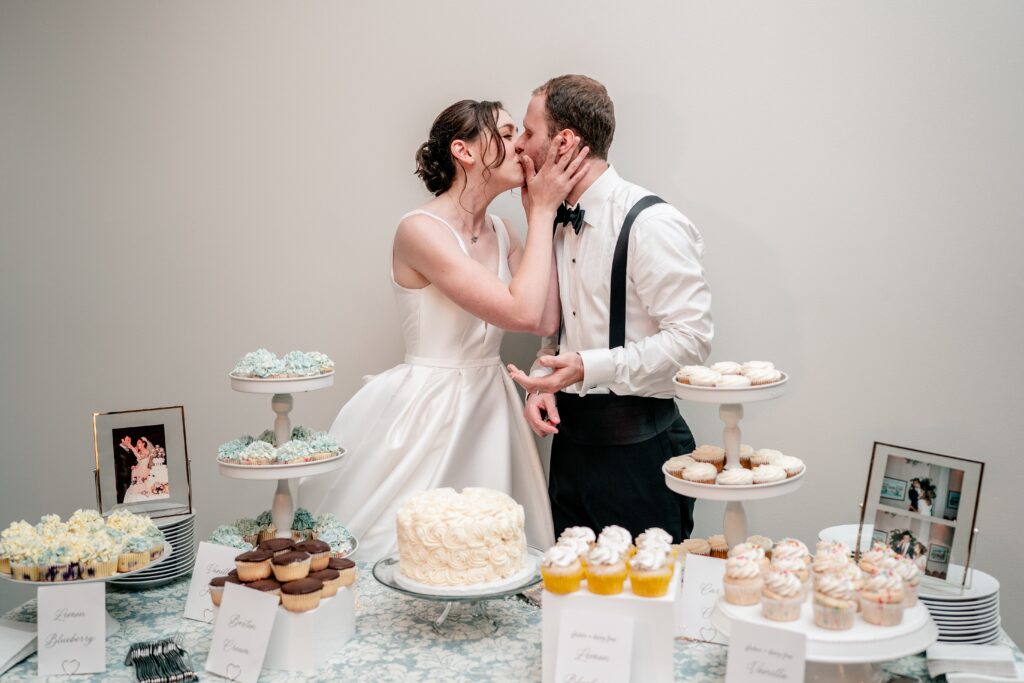 A bride and groom sharing a kiss at the cake table during their Sts. Peter and Paul Antiochian Orthodox Church wedding in Potomac, Maryland