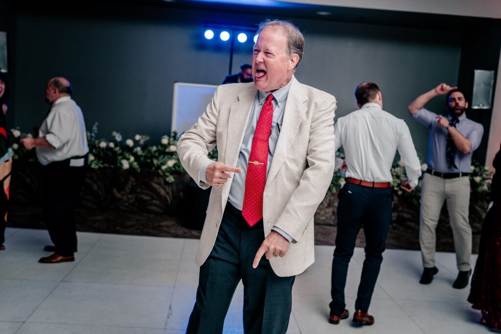 A wedding guest dancing with his tongue out and moving his hands