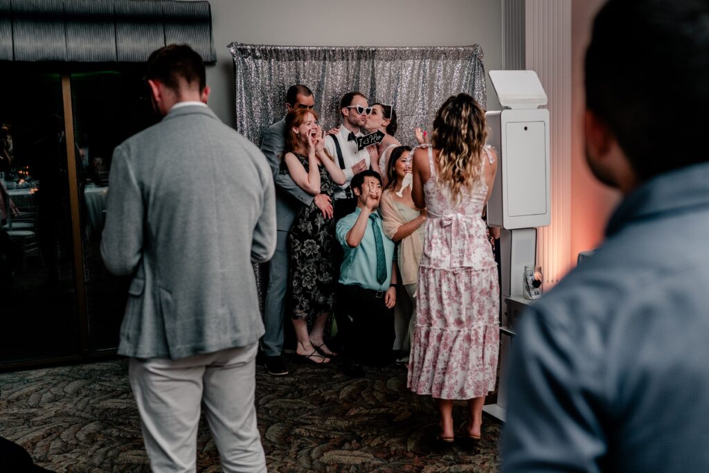 A photobooth with the bride and groom posing with guests during their Greek Orthodox wedding