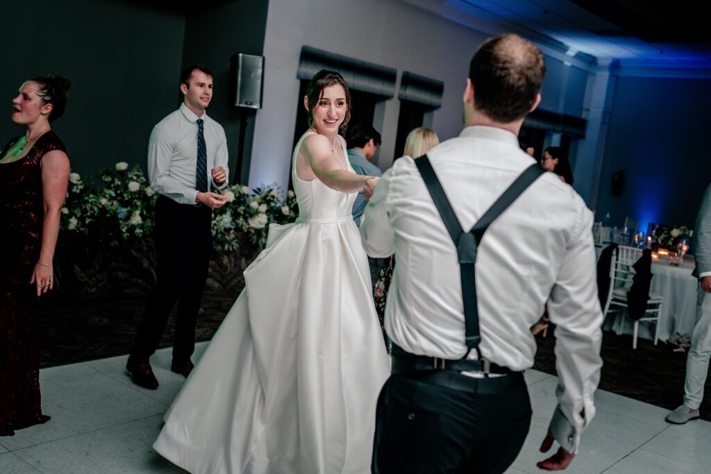 A bride and groom dancing together in front of their colorful wedding photographer