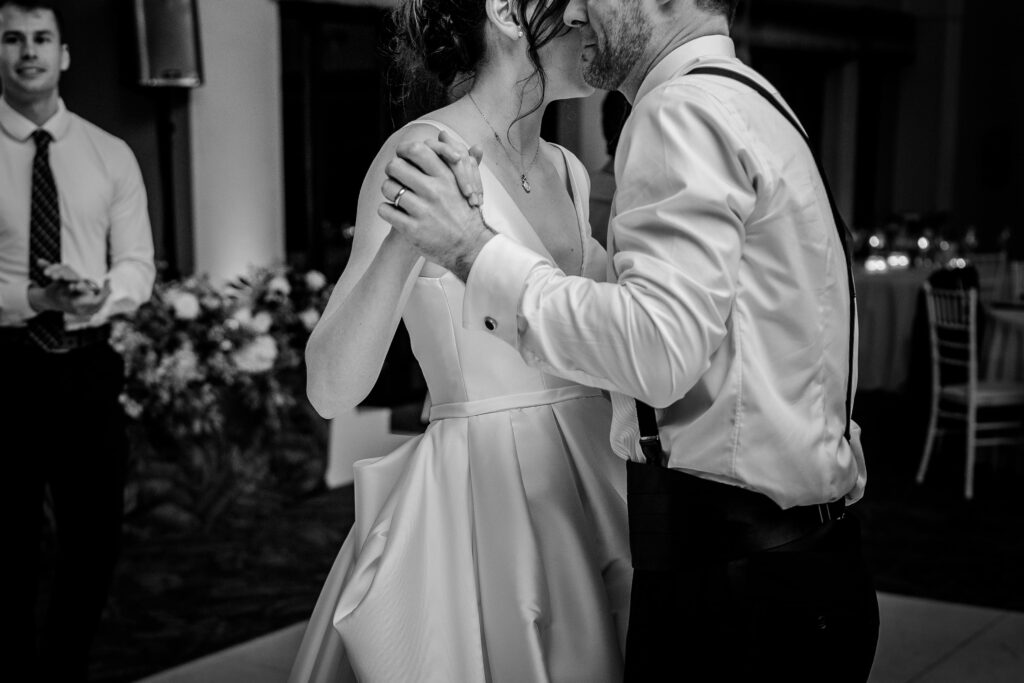A bride and groom holding hands as they dance together at their reception