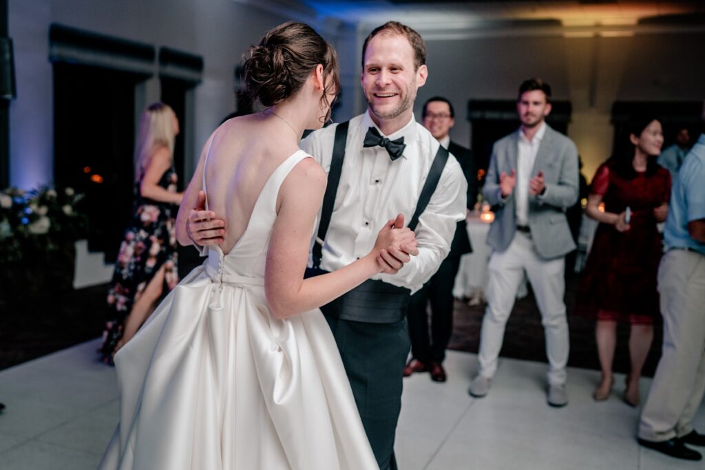 A groom smiling as he dances with his bride for their Greek Orthodox wedding
