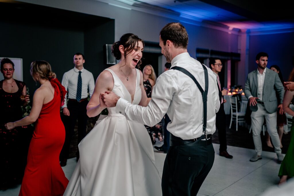 A bride laughing as she dances with her groom during their Greek Orthodox wedding