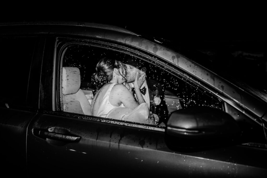A bride and groom sharing a kiss in the car at the end of their Greek Orthodox wedding