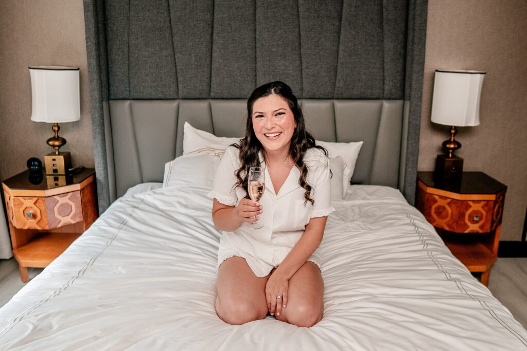 A bride posing with a glass of champagne before her Immaculate Conception Church wedding