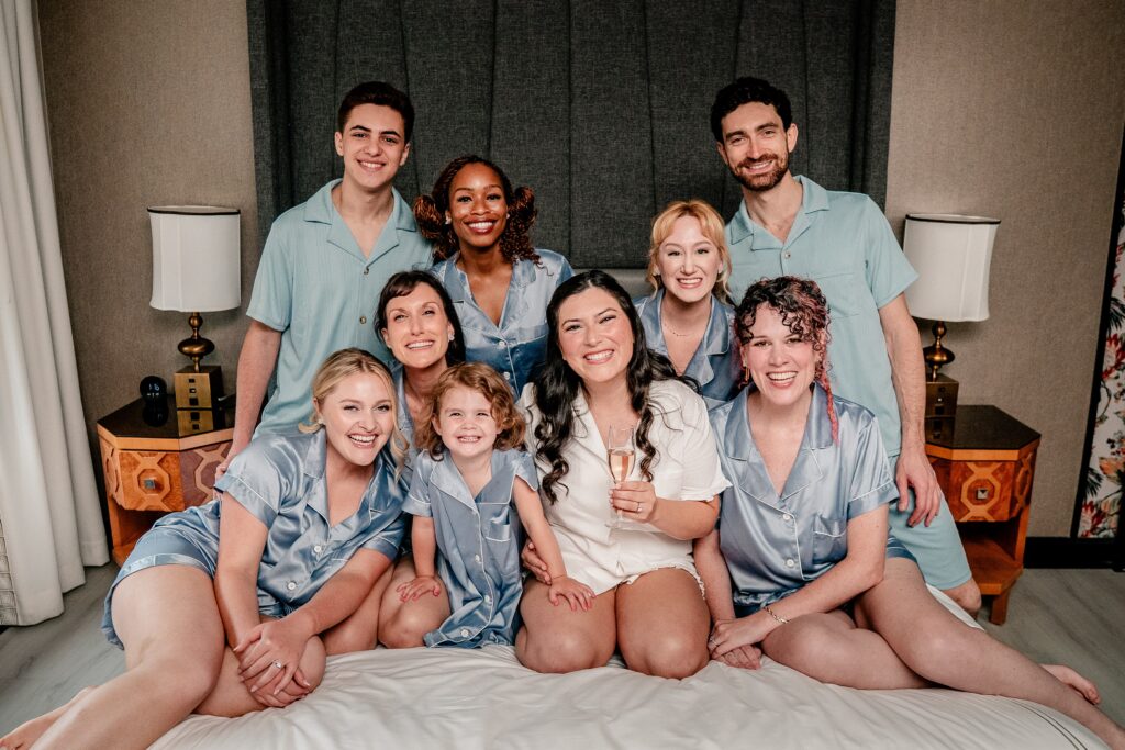 A bride and her bridal party posing on the bed with their Catholic wedding photographer