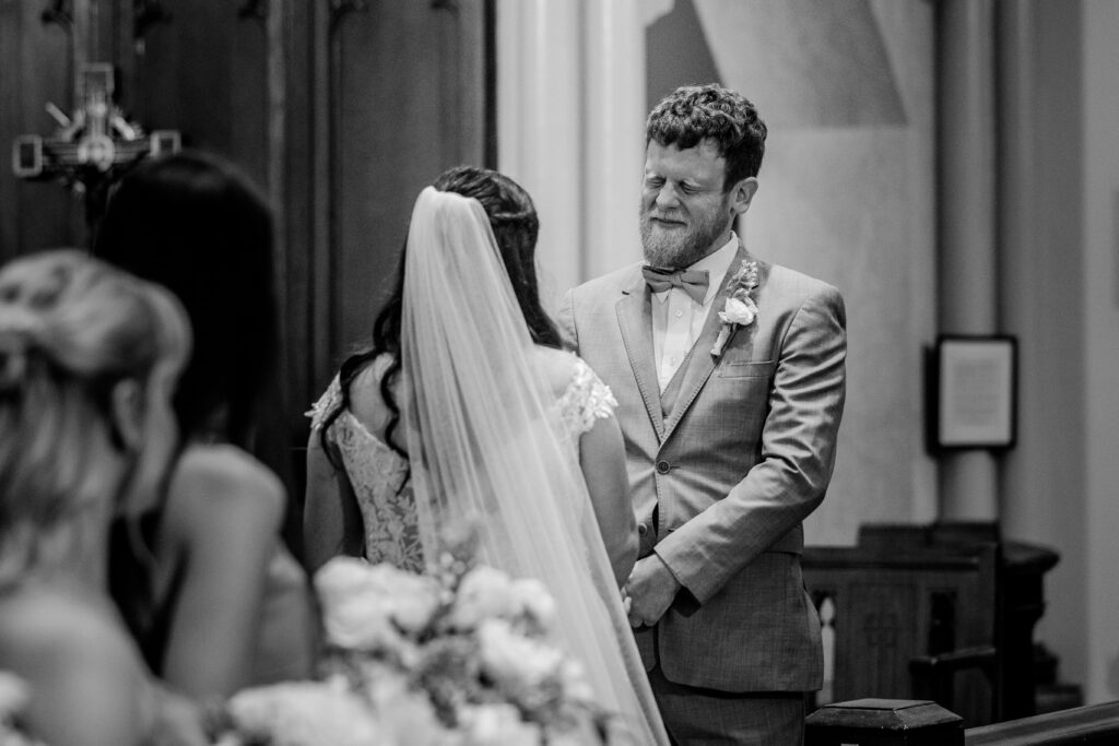 A groom holding back tears in a photo by a Catholic wedding photographer