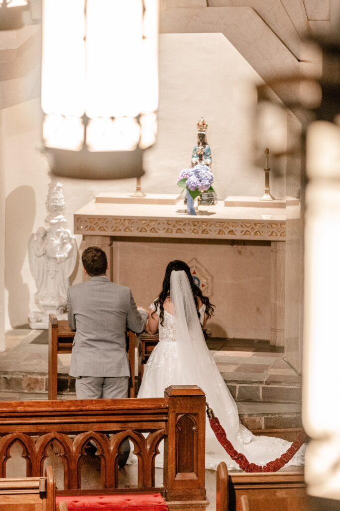 A bride and groom offering flowers to Mary during their Immaculate Conception Church wedding