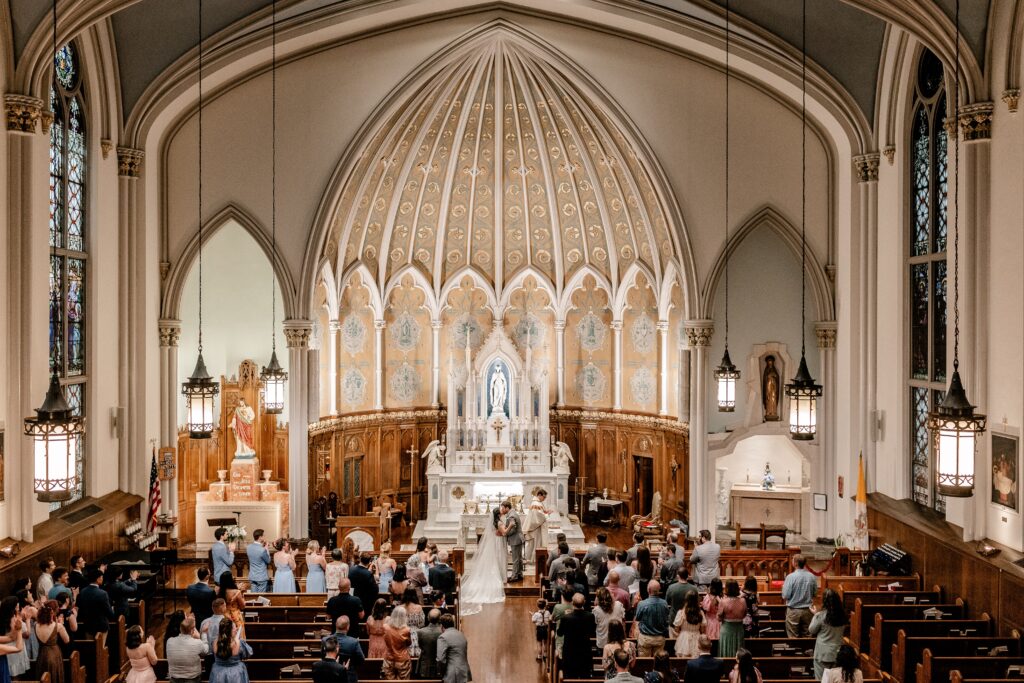 A view from the choir loft as a bride and groom share their first kiss as husband and wife