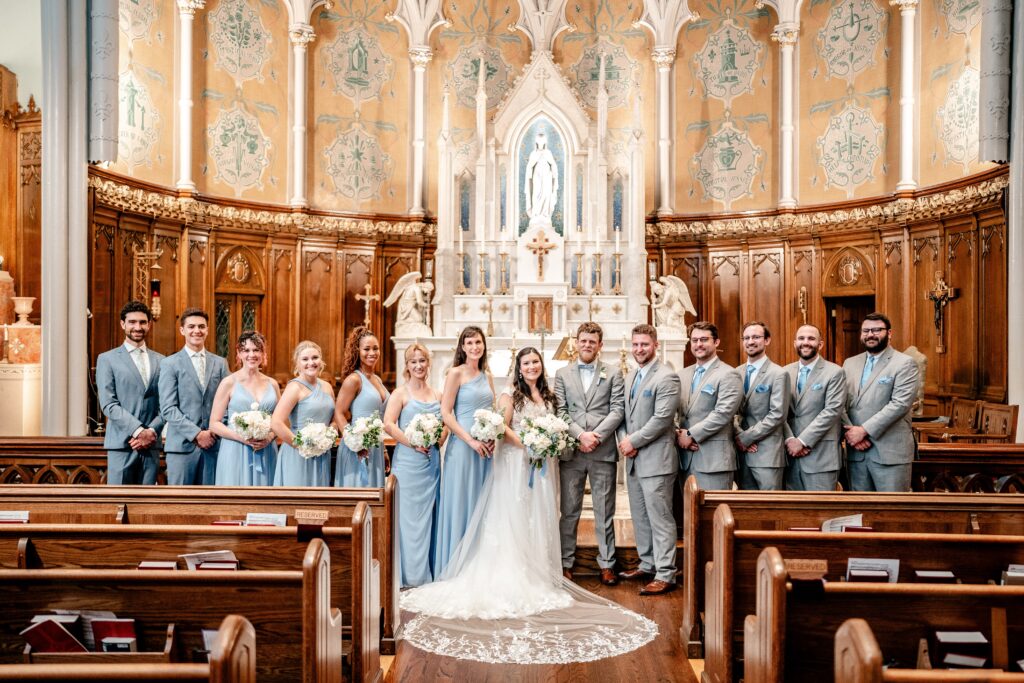 A wedding party wearing light blue standing in front of the altar for a posed portrait