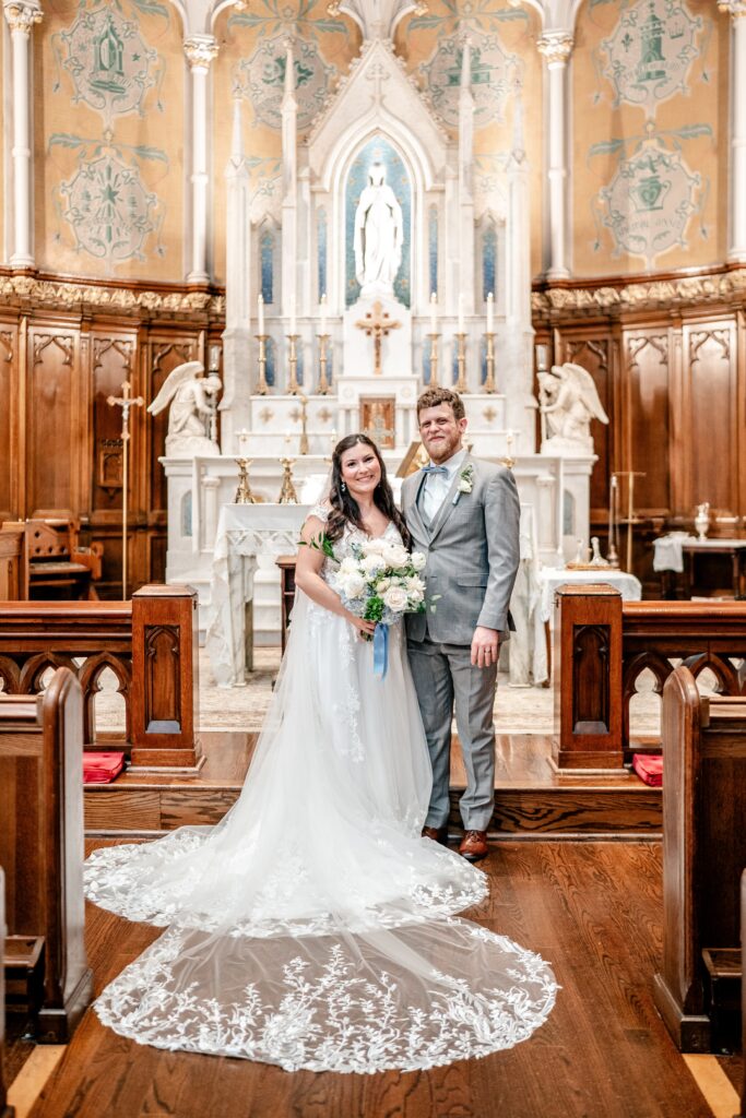 A bride and groom posed for a classic portrait in front of the altar of their church