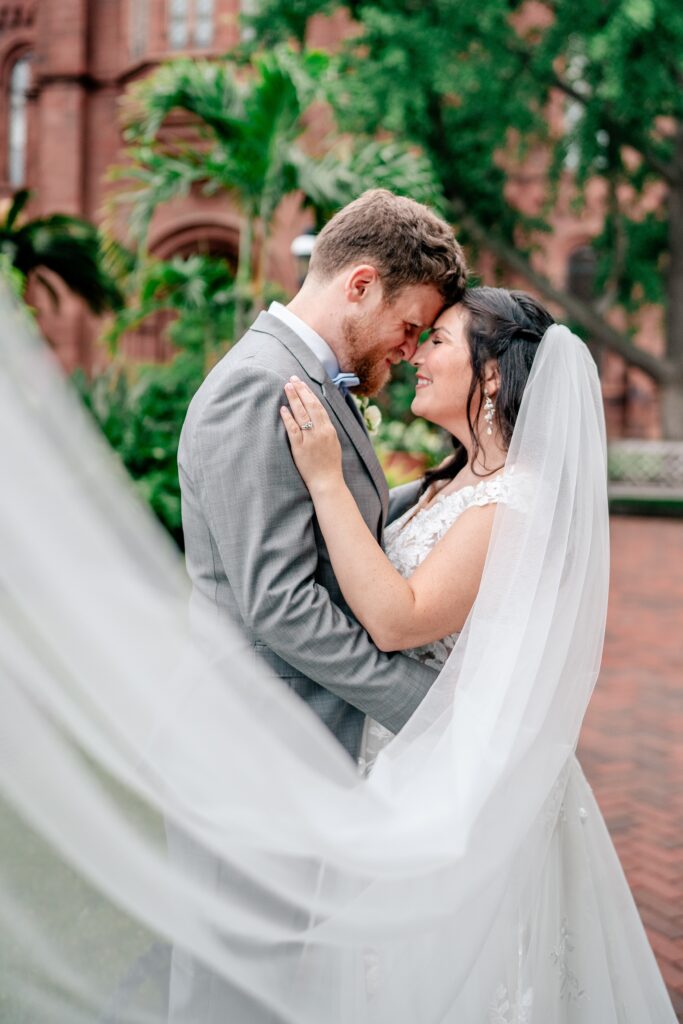 A bride and groom posing for a sweeping veil portrait after their Immaculate Conception Church wedding