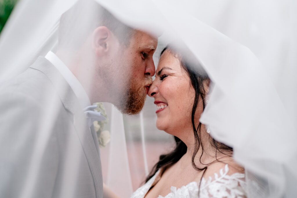 A groom kissing the nose of his bride for his Catholic wedding photographer