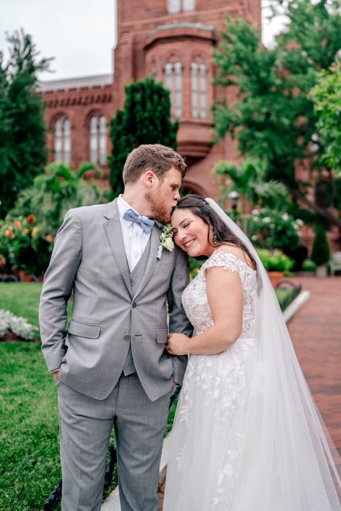 A groom kissing the top of his bride's head after their Immaculate Conception Church wedding