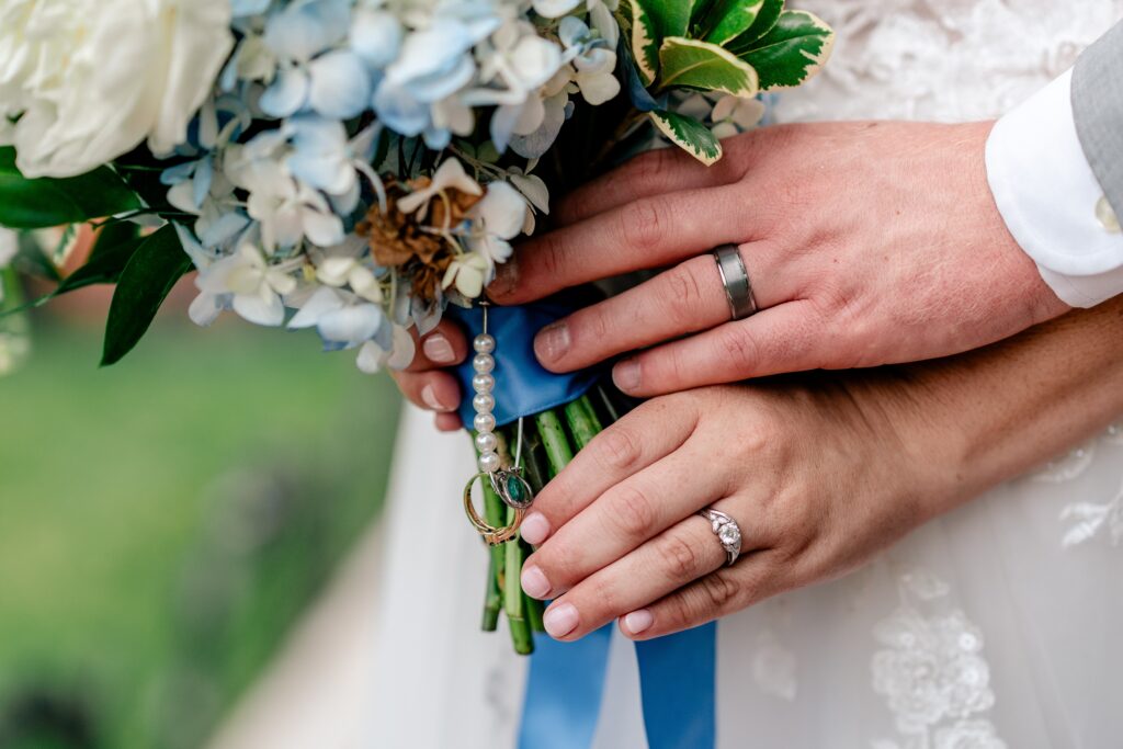 A close up of the bride and groom's hands holding her bouquet by a Washington DC wedding photographer