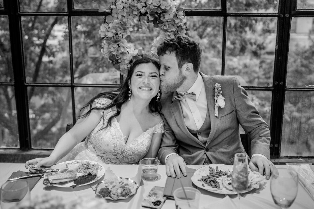 A groom kissing his bride on the cheek for his Catholic wedding photographer