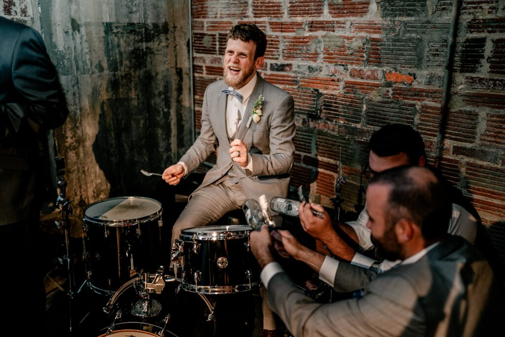 A groom playing the drums during his wedding reception