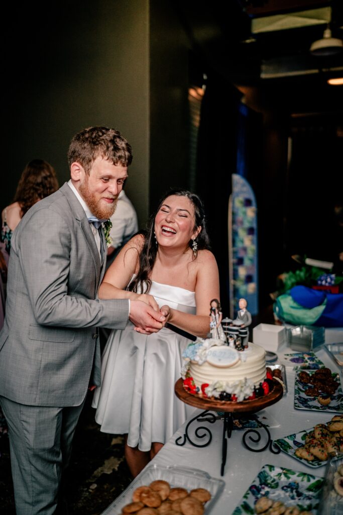 A bride and groom laughing during their cake cutting following their Immaculate Conception Church wedding