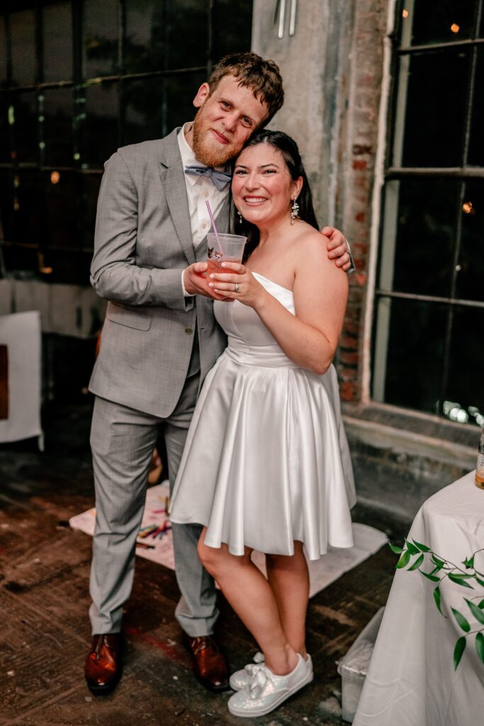 A bride and groom pose for a cheesy picture together at their reception by their Washington DC wedding photographer