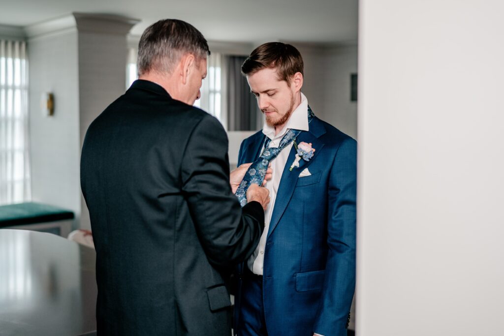 The father of the groom fixing the groom's tie before his wedding