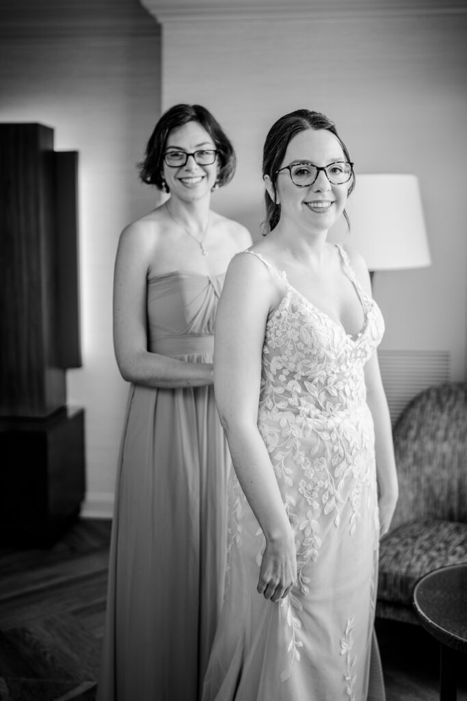 A bride and her sister smiling as they get ready for her wedding