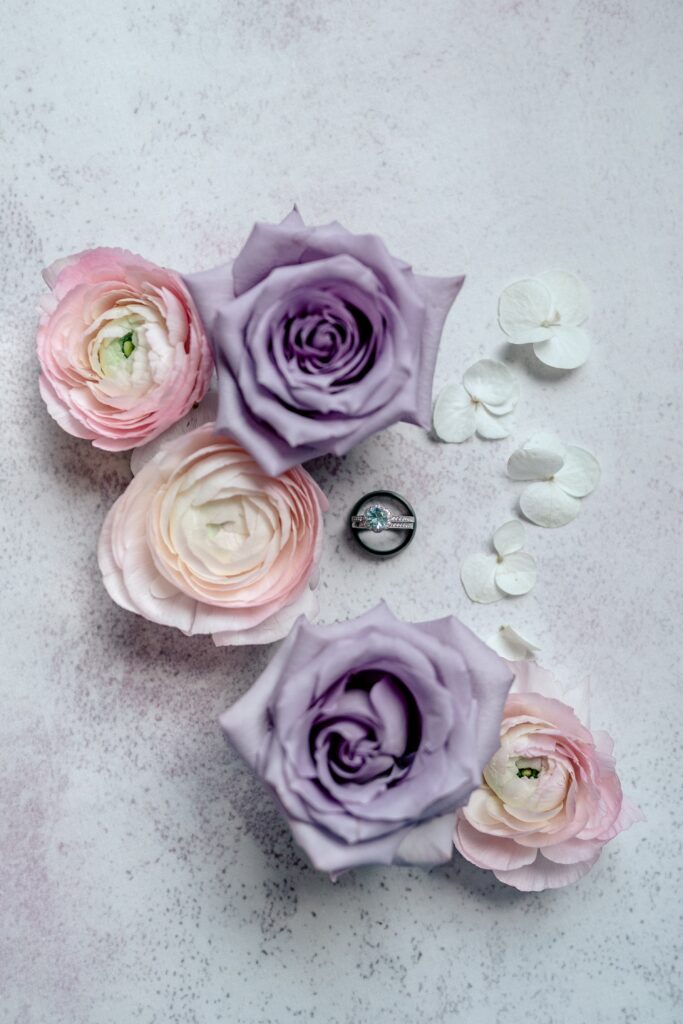 A wedding ring set surrounded by pink and purple flowers before a Meadowlark Botanical Gardens wedding