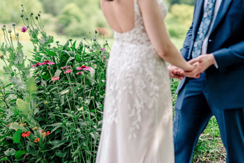 A garden of pink flowers in front of a bride and groom holding hands during their Meadowlark Botanical Gardens wedding