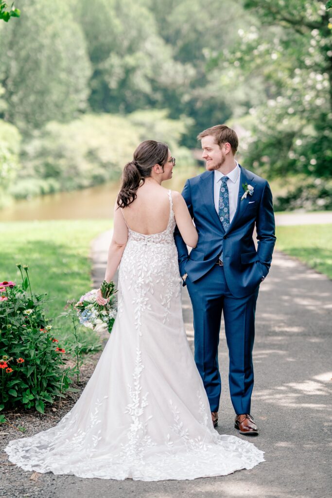 A bride shows off the back of her dress and smiles at her groom