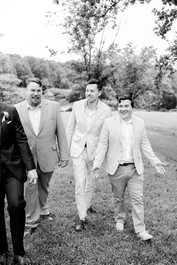 Groomsmen laugh candidly as they walk beside the groom