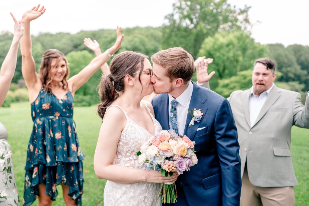 A wedding party cheers as the bride and groom share a kiss during their Atrium at Meadowlark wedding