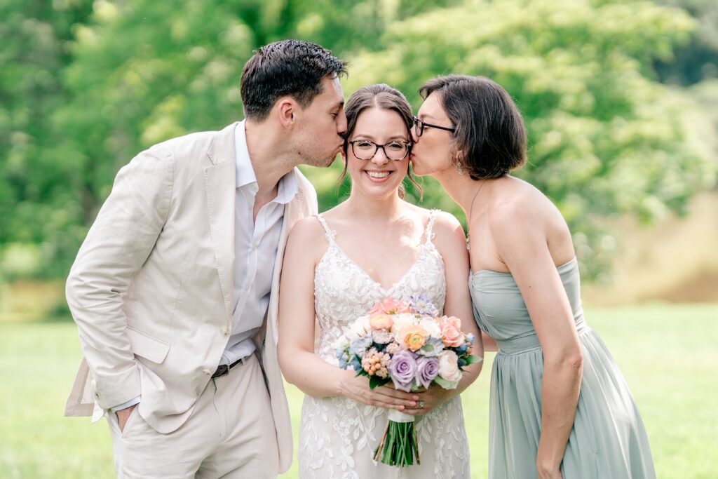 A bride's two siblings kiss her cheeks during her Meadowlark Botanical Gardens wedding