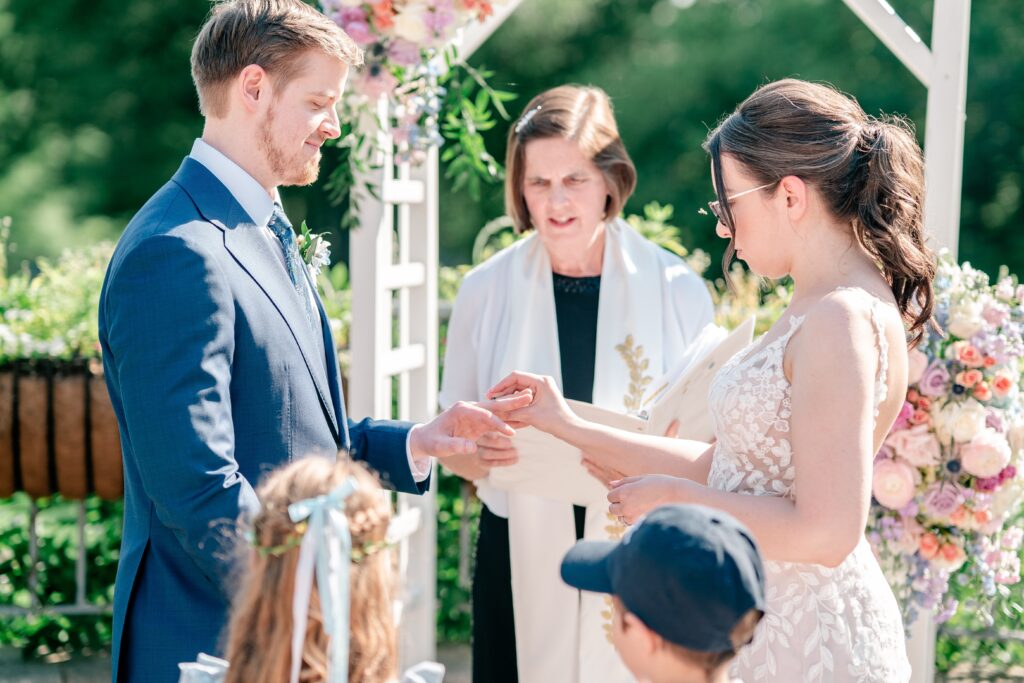 A bride and groom exchanging rings during their outdoor wedding ceremony