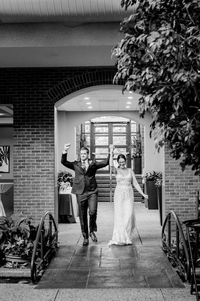 A bride and groom cheering as they enter their wedding reception
