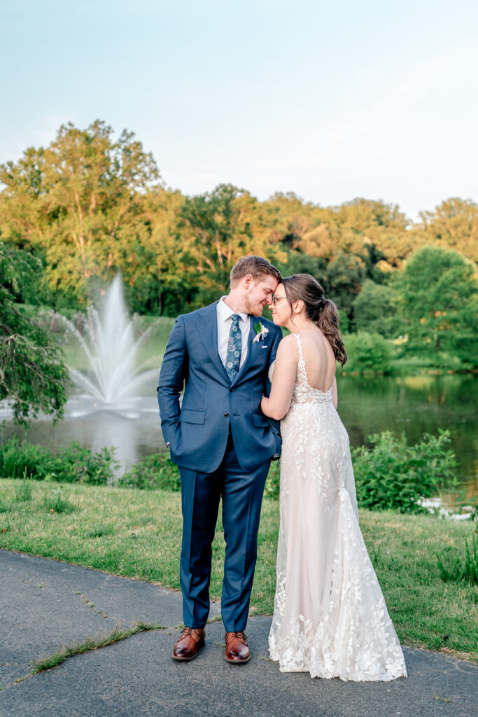 A bride and groom standing forehead to forehead in front of a fountain by a Northern Virginia wedding photographer