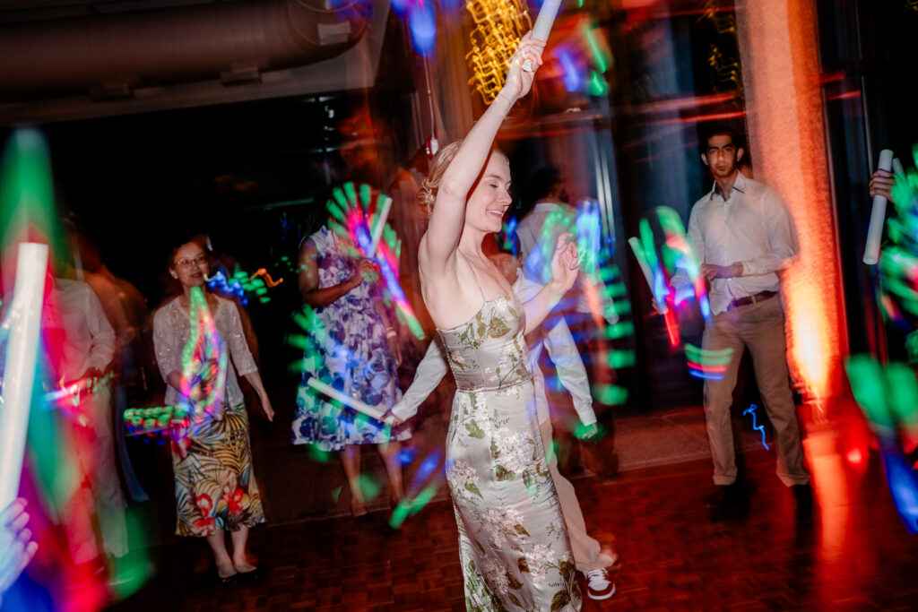 A bridesmaid dancing and waving a glow stick in a shutter drag photo