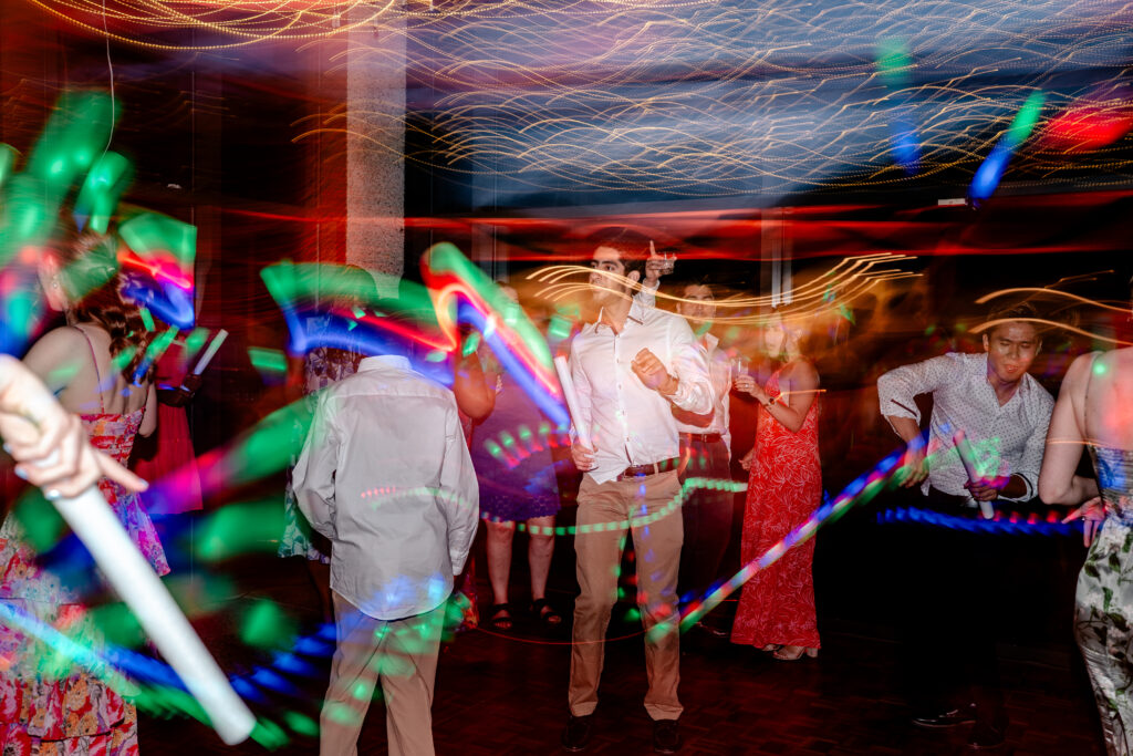 A wedding reception with glow sticks in a shutter drag photo