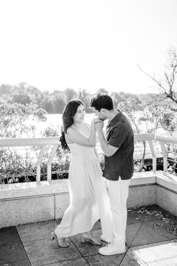 A man kissing his partner's hand as she smiles at him at one of the best places to take engagement photos in DC