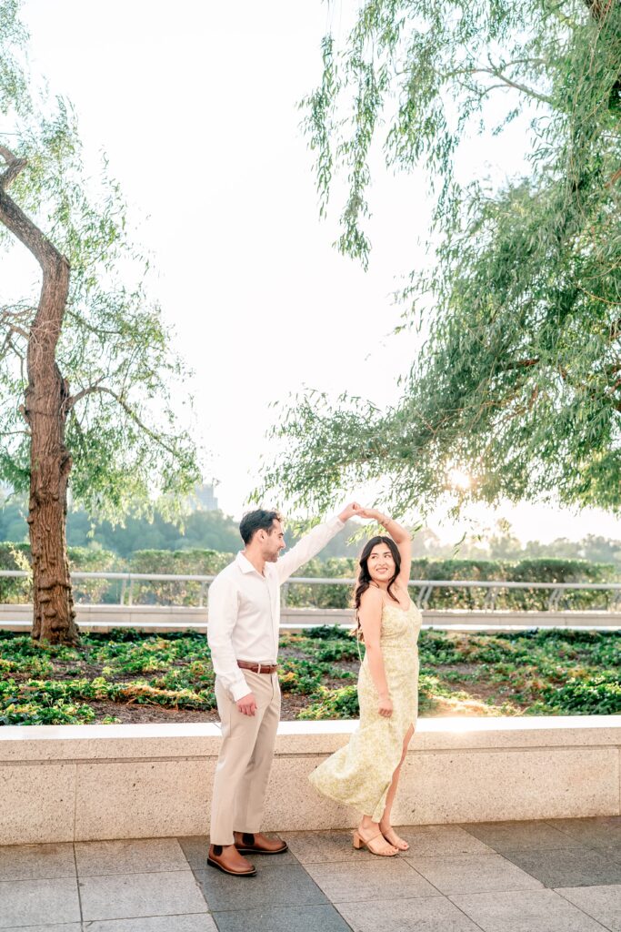 An engaged couple twirling on a terrace at golden hour