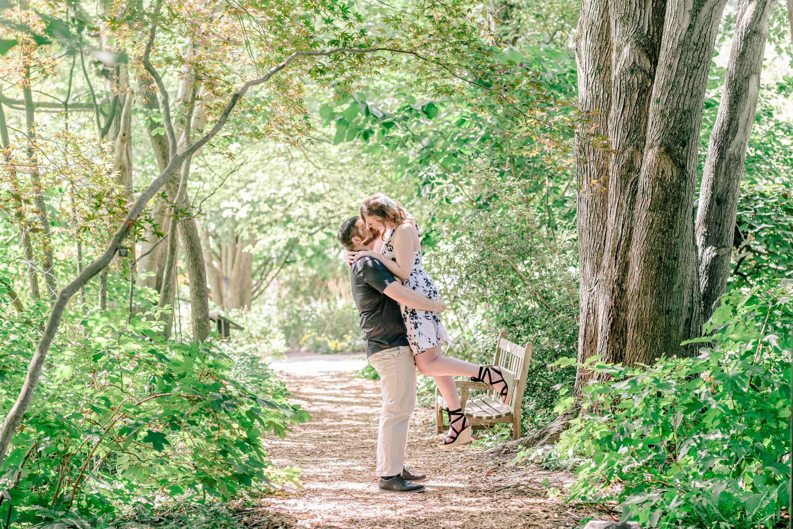 An engaged couple shares a dramatic kiss as the man lifts his partner off her feet during their Meadowlark Botanical Gardens engagement photos