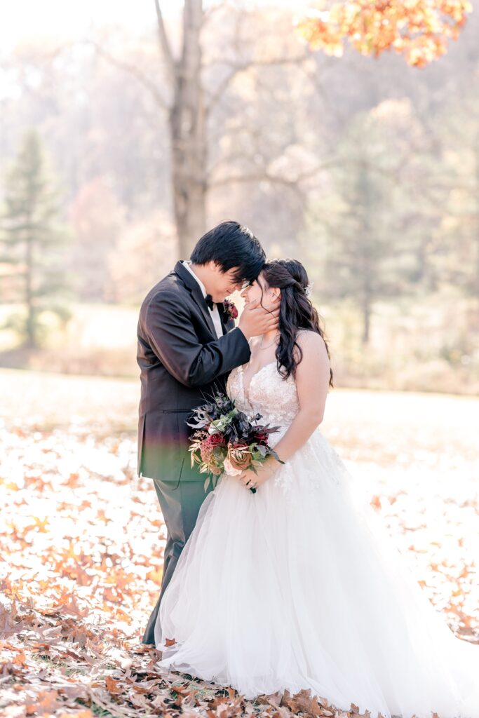 A bride and groom posed among autumn leaves for their Northern VA wedding photographer
