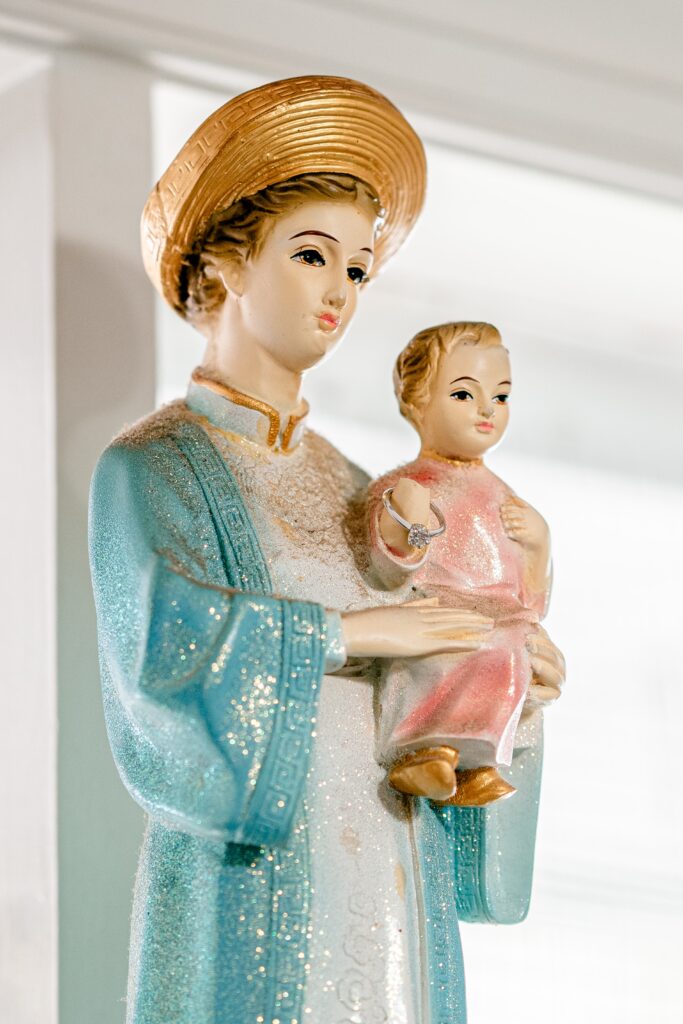 An engagement ring resting on a religious statue before a Murray Hill wedding